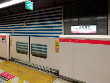 Metro istasyonu platformu tren kapılarını ve tabelaları gösteriyor.