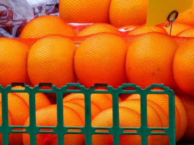 Yeşil plastik sandığın arkasında taze portakallar var.