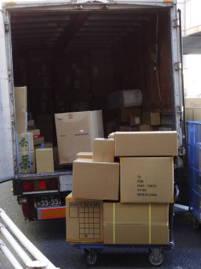 Yığınla karton kutu gün ışığında hareket halindeki kamyonu dolduruyor.