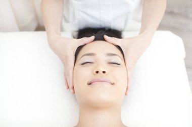 Asyalı kadın kafa masajı yaptırıyor, kaplıcada dinleniyor.