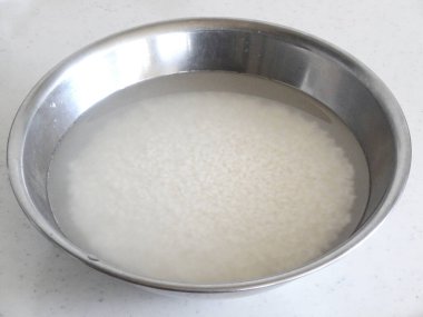 Bir kase pirinç ve metal kasede su. 