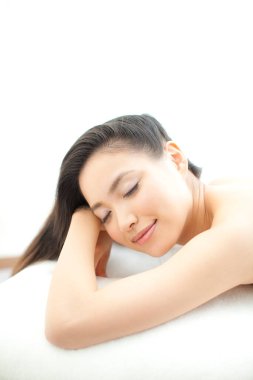 Güzel Asyalı kadın gözleri kapalı yatakta yatıyor.