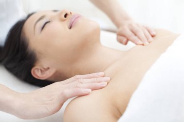 Güzel Asyalı kadın spa salonunda yüz masajı yaptırıyor.