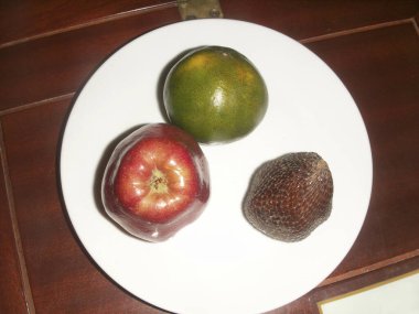 Beyaz tabakta üç meyve.