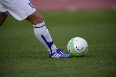 Bir futbolcu sahada futbol topunu tekmeliyor.