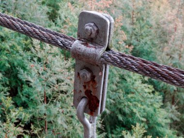 Kapalı çekimde paslı metal kablo kıskacı açık havada kalın kabloyu emniyete alıyor.