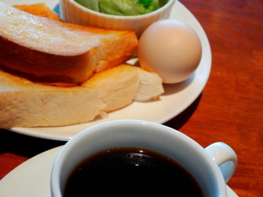 Bir fincan kahve ve kızarmış ekmek ve haşlanmış yumurta ile sağlıklı bir kahvaltı.  