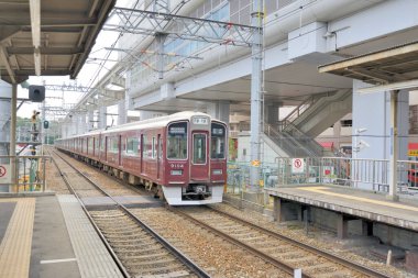 Kırmızı banliyö treni modern açık hava tren istasyonuna yanaşıyor.