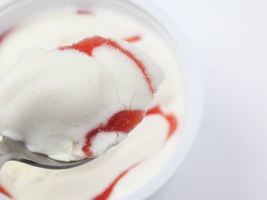 Beyaz kasede kaşık içinde çilekli yoğurt.