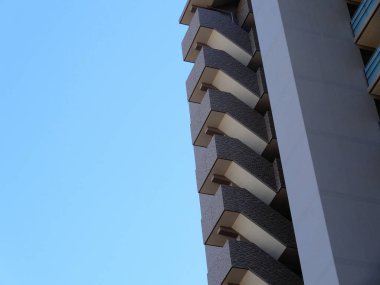 Arka planda balkonları olan bir apartmanın ön cephesi.