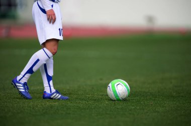 Bir futbolcu sahada futbol topunu tekmeliyor.