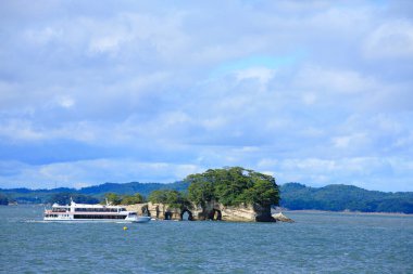 Bereketli yeşil bitki örtüsüyle kayalık adalara yaklaşan bir gemi. Miyagi Bölgesi, Japonya 'daki Matsushima Adaları