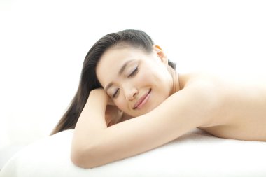 Güzel Asyalı kadın gözleri kapalı yatakta yatıyor.