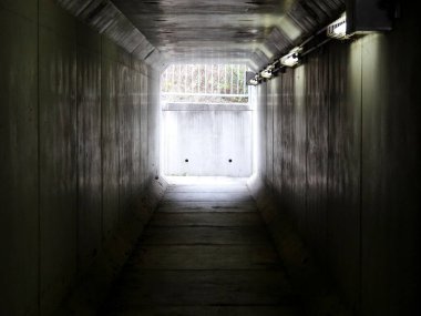 Gri duvarları ve ışığı olan yeraltı tüneli 