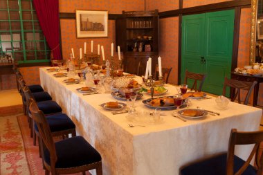 Zarifçe hazırlanmış yemek masası. Mumlar, tabaklar, klasik dekorlar.