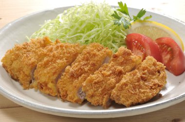 Kızarmış pirzola dilimleri dilimlenmiş lahana domatesli limonlu garnitür.