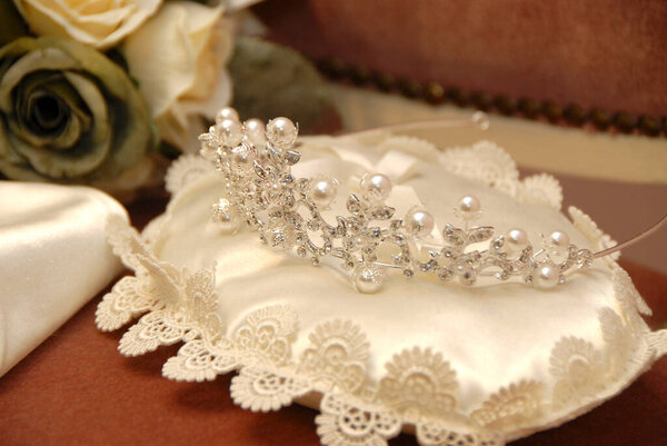 Delicate pearl tiara resting on elegant lace pillow