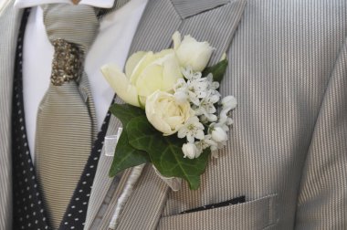Damadın şık takım elbiseli ve düğün yaka çiçekli yakın çekimi.    