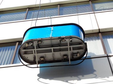 Binanın önünde asılı duran mavi askıya alınmış pencere temizleme platformu