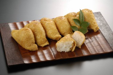 Tahta tepside duran altı altın inari suşi parçası.