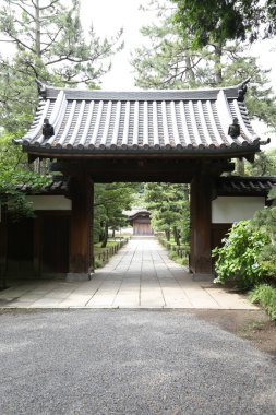 Geleneksel Japon ahşap kapısı huzurlu bahçe yoluna açılıyor.