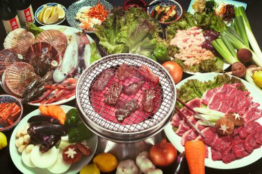 Izgara et tabağını çevreleyen çeşitli taze deniz ürünleri.