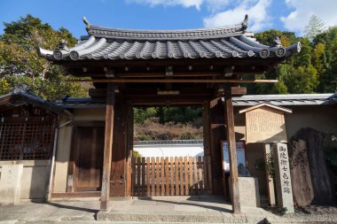 Geleneksel Japon ahşap kapısı dışarıda taş duvarın önünde duruyor.