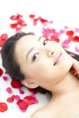 Beyaz arka planda kırmızı çiçek yaprakları olan kadın.