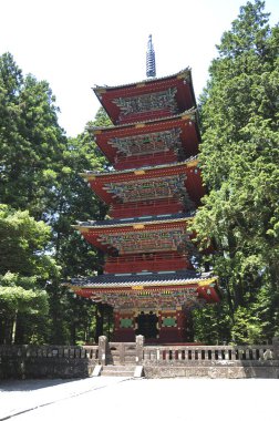 Açık havada yemyeşil ağaçların arasında duran uzun kırmızı pagoda