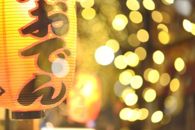 Bulanık altın festival ışıkları arasında parlayan Japon feneri.