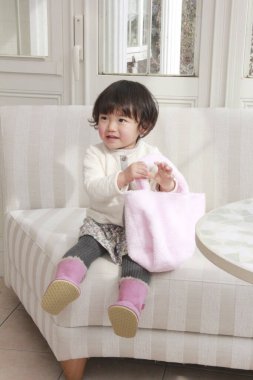 Evinde pembe tekstil çantası tutan sevimli Asyalı küçük kız.