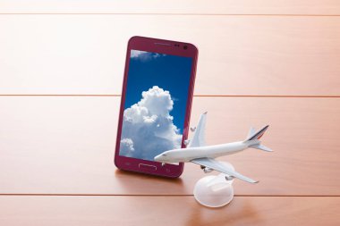 Ahşap masada oyuncak uçakla cep telefonu.