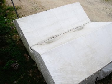 Çimenli zemindeki yapıları kaplayan büyük beyaz brandalar