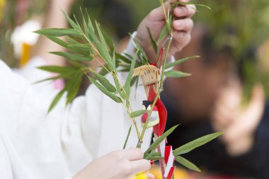 Tören sırasında elinde süslü bambu dalı tutan kişi