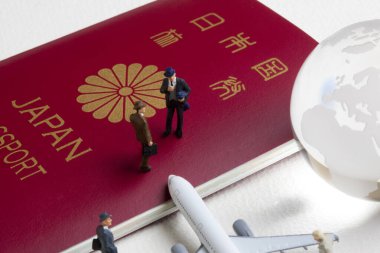 Oyuncak uçak, cam dünya küresi ve Japon pasaportlu minyatür insanlar.