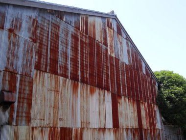 Paslı metal ahır duvarı dışarıda yıpranmış yuvarlak panelleri gösteriyor.