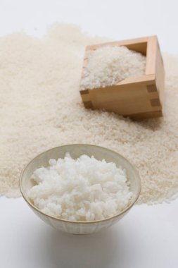 Beyaz kase pirinç ve ahşap masada pişmemiş pirinç.