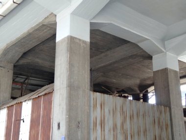 Beton sütunlar bükülmüş metal çitin üstündeki yüksek yapıyı destekliyor.