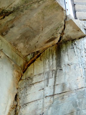 Çatlamış beton yapı hava durumunu ve su lekelerini gösteriyor.