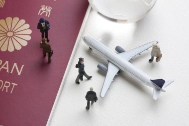 Oyuncak uçak, cam dünya küresi ve Japon pasaportlu minyatür insanlar.