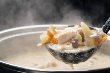 Sıcak çorba serin sonbahar mevsiminde sıcak bir mutfakta buharlı bir tencerede servis ediliyor.