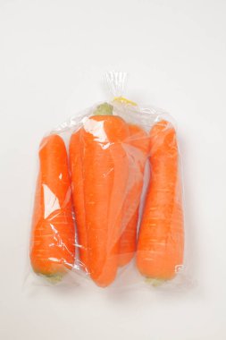 Beyaz üzerinde taze havuç olan plastik torba.