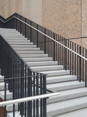 Modern beton merdiven. Siyah metal parmaklıklar açık havada yükseliyor.