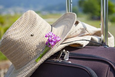 Bavulunda pembe çiçek olan hasır şapka, seyahat konsepti. 