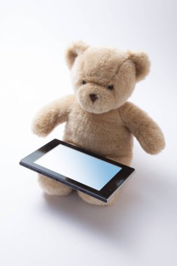 Beyaz arkaplanda tablet bilgisayarı olan oyuncak ayı 