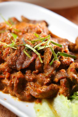 Serving spicy beef dish garnished with herbs