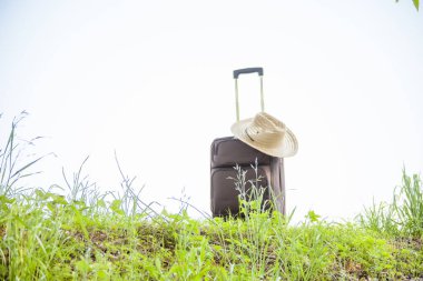 Açık havada duran hasır şapkalı bavul, seyahat kavramı.