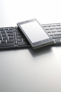 Beyaz arkaplanda bilgisayar klavyesinin ve cep telefonunun yakın görüntüsü                 