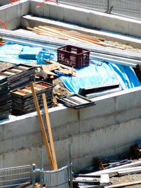 Dışarıdaki beton temel duvarlarının üzerinde istiflenmiş inşaat malzemeleri.