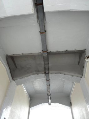 Yürüyüş yolunun üzerinde uzanan metalden bir boruyla gri boyalı tavan.